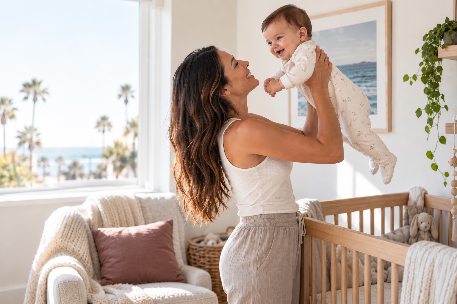 A mother lifting her smiling baby from a crib in a bright coastal nursery